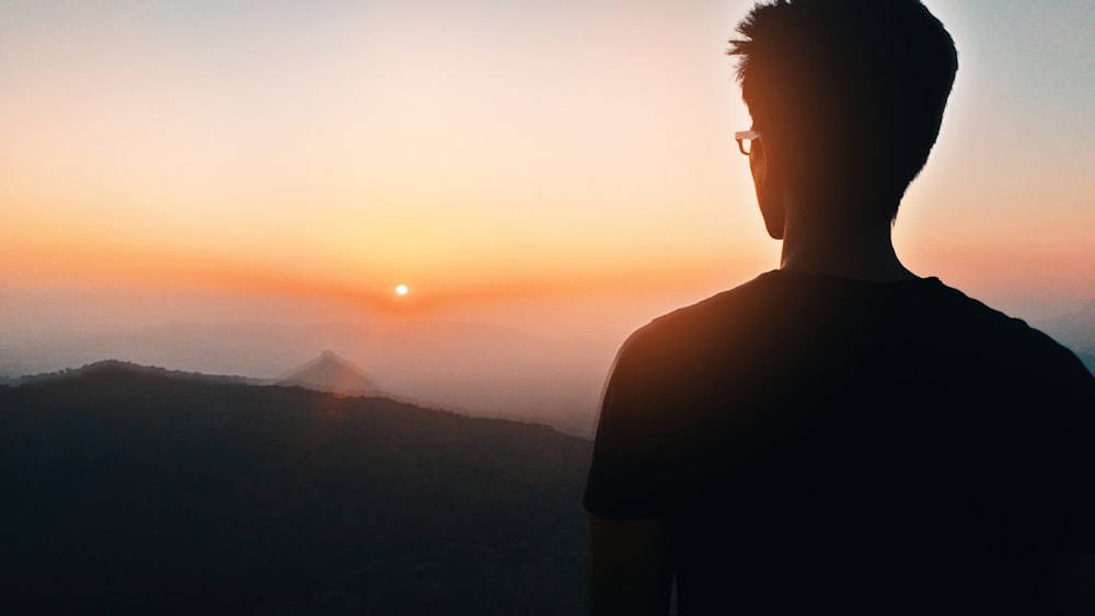 Silueta del hombre mirando hacia la montaña en la hora dorada