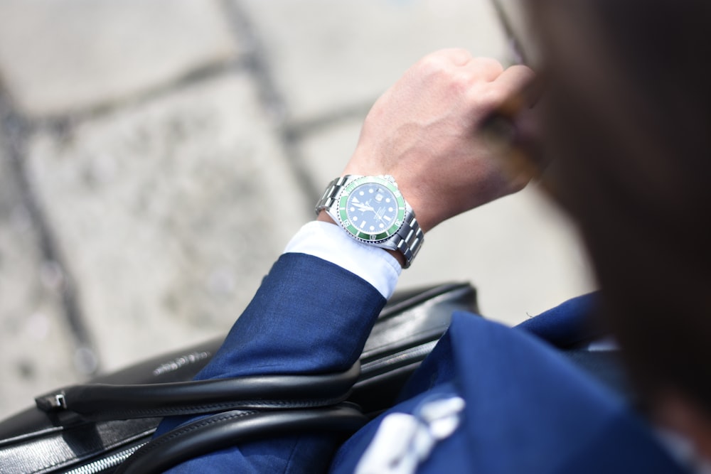 person looking at silver-colored analog watch