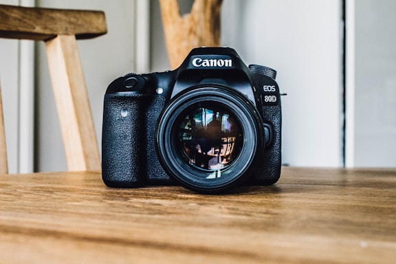 Canon DSLR camera on brown wooden table during daytime