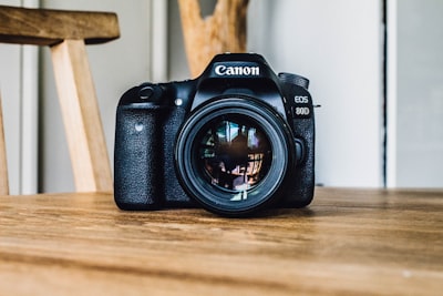 canon dslr camera on brown wooden table during daytime camera teams background