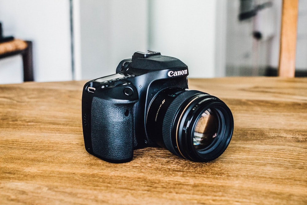 fotocamera reflex digitale Canon nera su superficie in legno