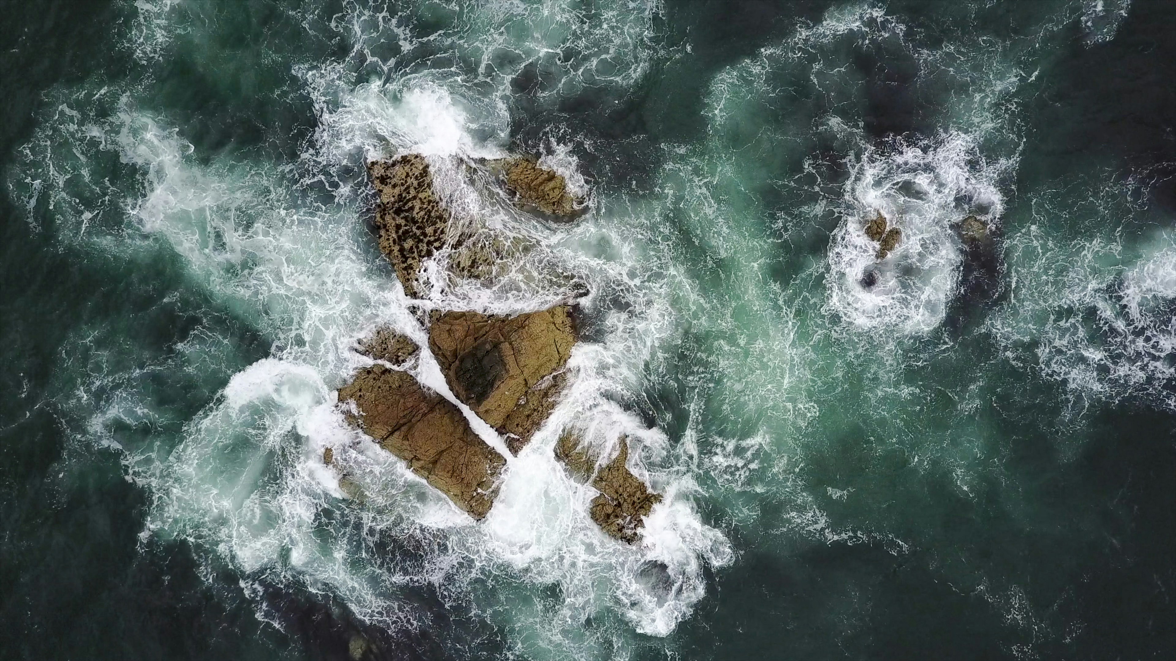 rock formation surrounded by body of water in aerial photography