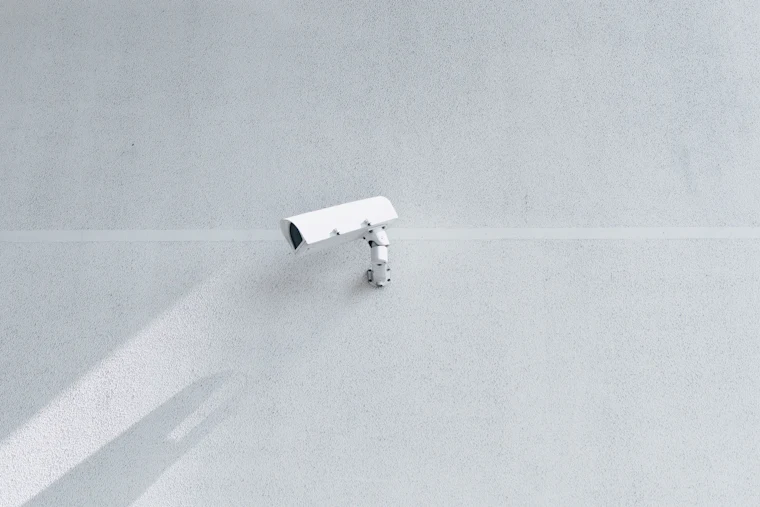 Compact white security camera on a plain wall