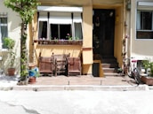 A welcoming front porch of a rental home with potted plants and a comfortable seating area.