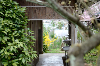 A beautifully designed outdoor bathroom featuring natural stone and custom metal accents under a pergola.