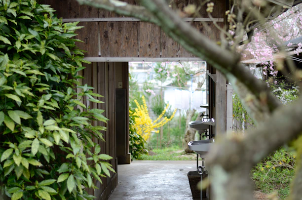 A beautifully designed outdoor bathroom featuring natural stone and custom metal accents under a pergola.