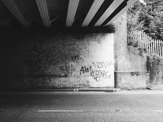 Close-up of a gritty graffiti wall with a bold urban t-shirt draped over a metal fence.