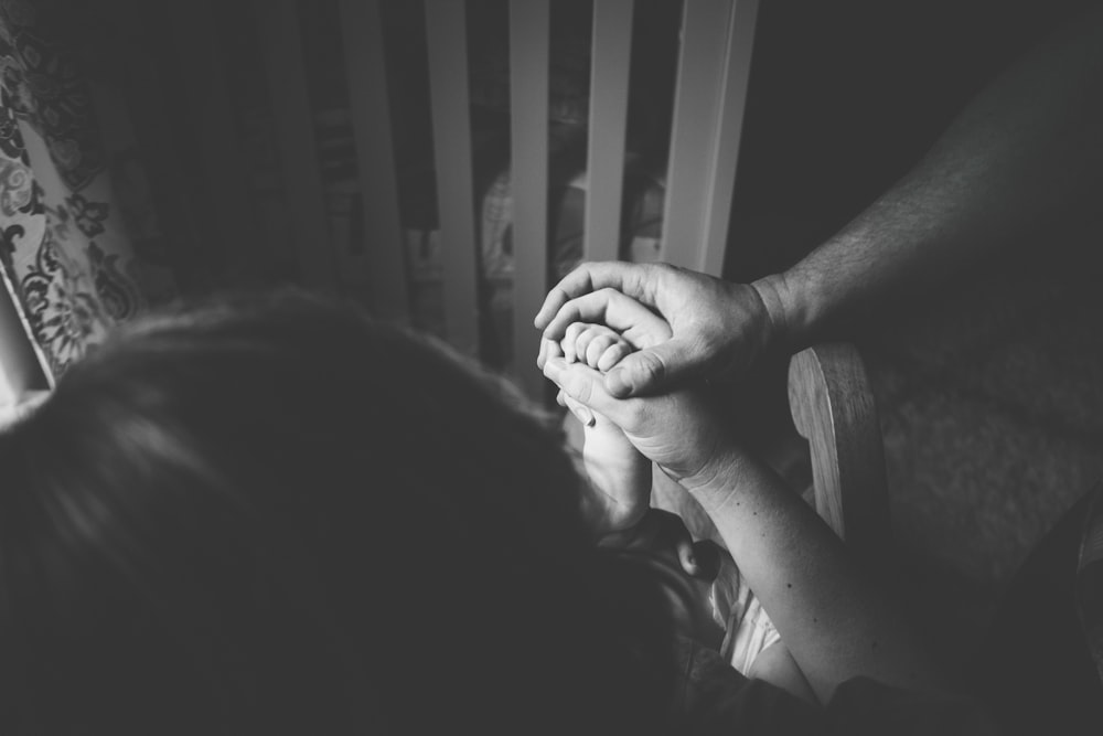 greyscale photo of person holding woman's hand