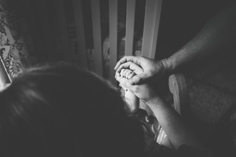 Photo en niveaux de gris d’une personne tenant la main d’une femme