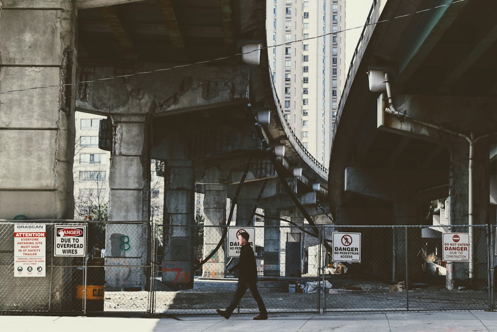person walking under city bridge