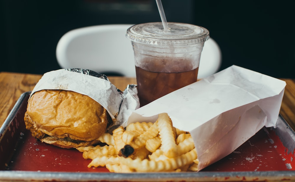 burger beside fried potatoes with drinking glass