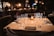 A cozy dining table set with elegant tableware and a flickering candle in a warm restaurant ambiance.