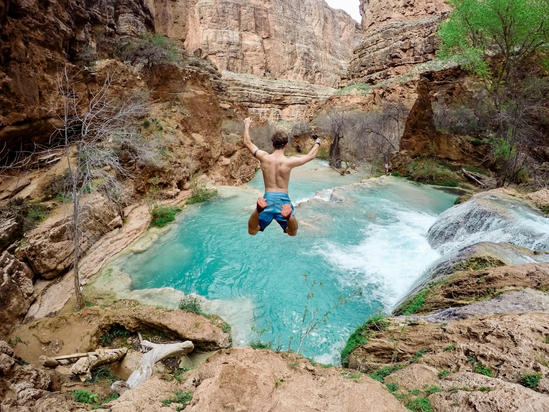 time lapse photography of man jumping on waterfalls