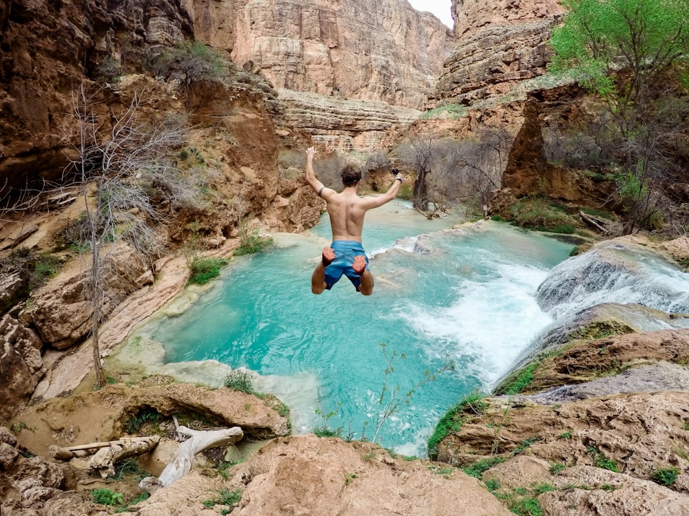 time lapse photography of man jumping on waterfalls