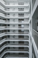 A multi-story building interior with floors clearly labeled from 35 to 49. Each level has a minimalist design with white walls and metal railings. The perspective is from an upper floor looking down, showing a series of levels with recessed balconies.