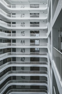 A multi-story building interior with floors clearly labeled from 35 to 49. Each level has a minimalist design with white walls and metal railings. The perspective is from an upper floor looking down, showing a series of levels with recessed balconies.