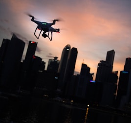 silhouette of quadcopter drone hovering near the city