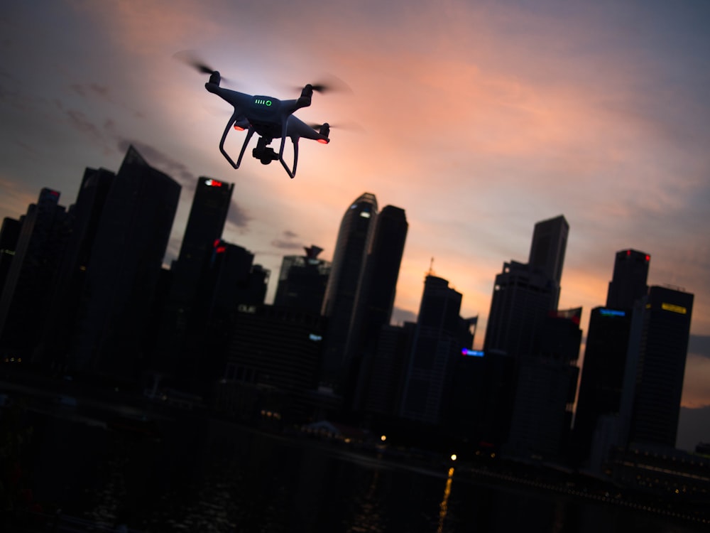 Silhouette einer Quadrocopter-Drohne, die in der Nähe der Stadt schwebt