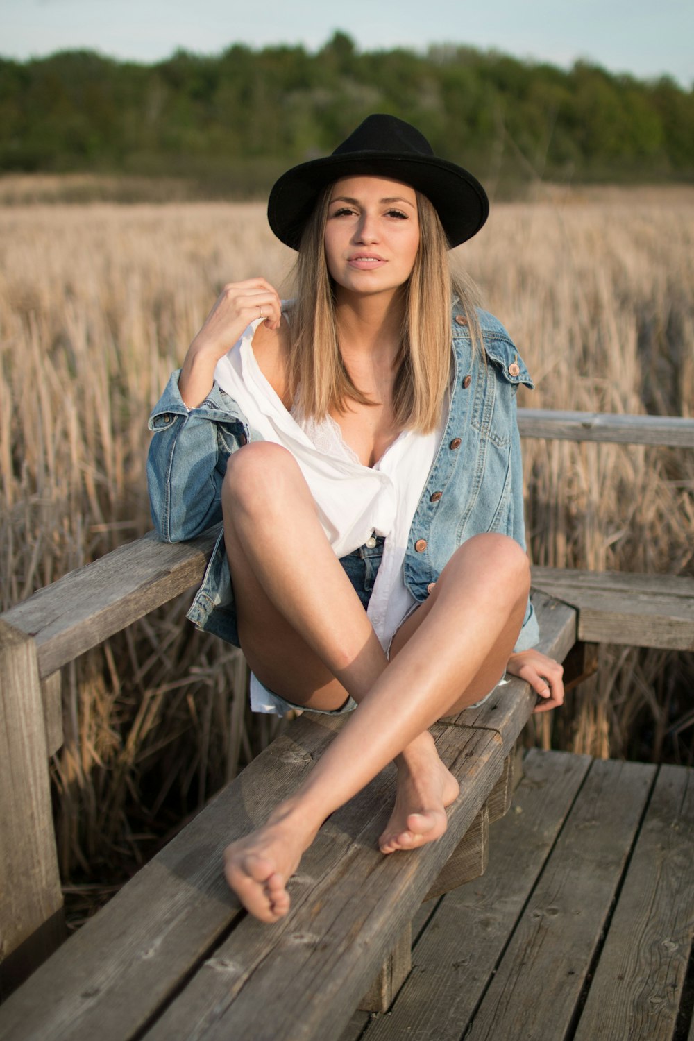 woman sits on wooden bench near field