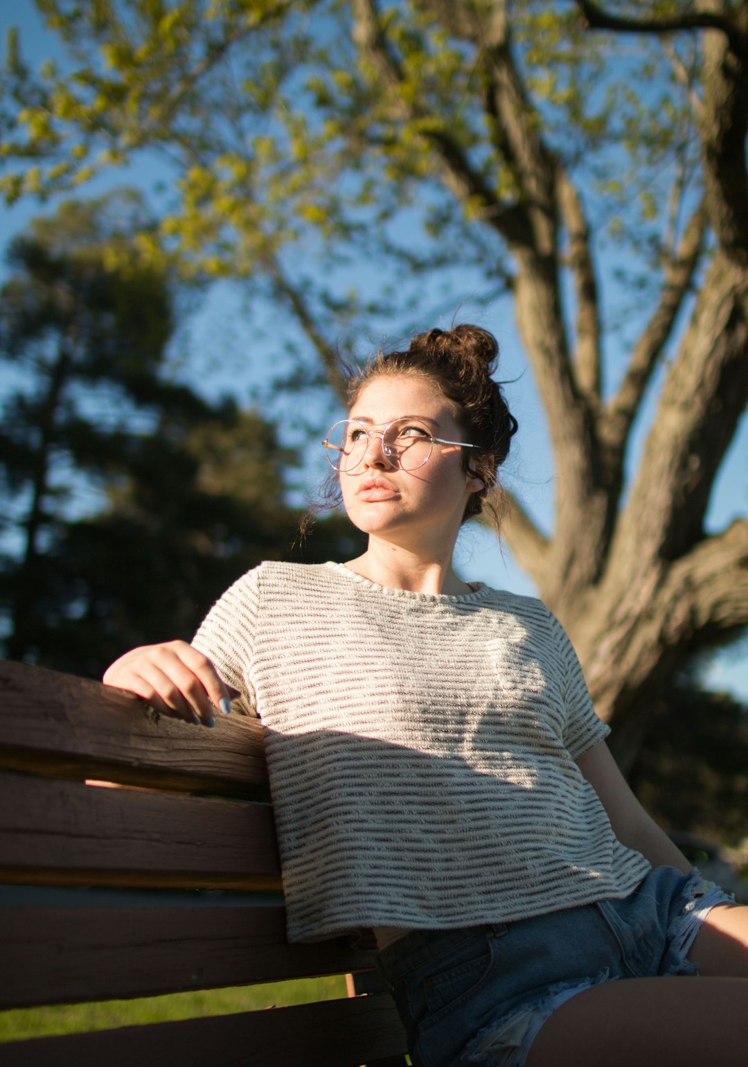 selective focus photography of girl sitting on bench during daytime