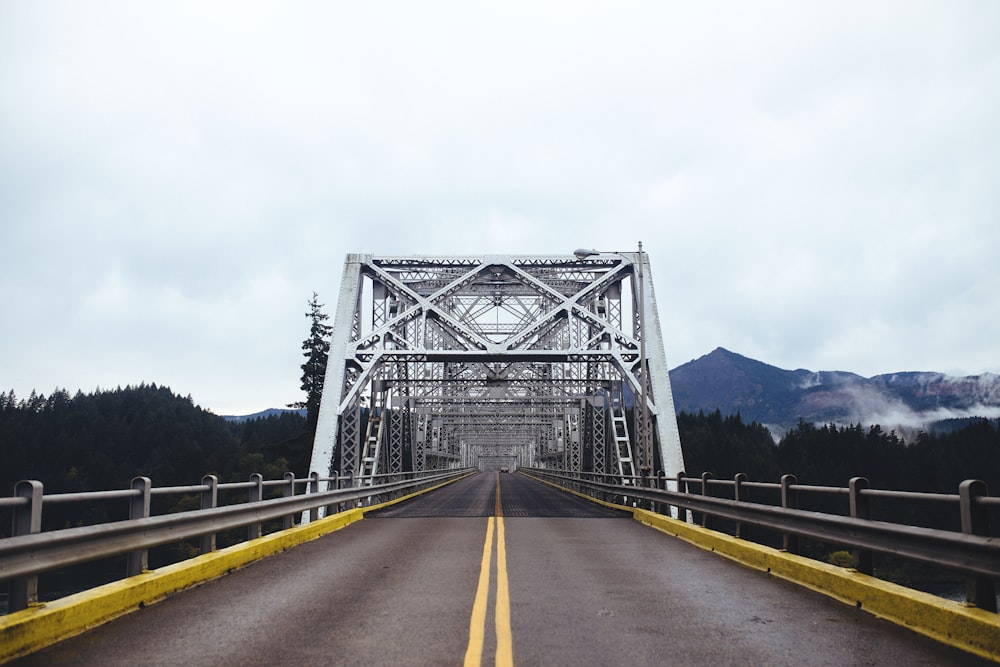 white and gray steel bridge with two yellow lanes