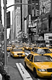 A fleet of yellow taxis parked in a bustling urban area.