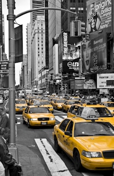 A fleet of yellow taxis parked in a bustling urban area.