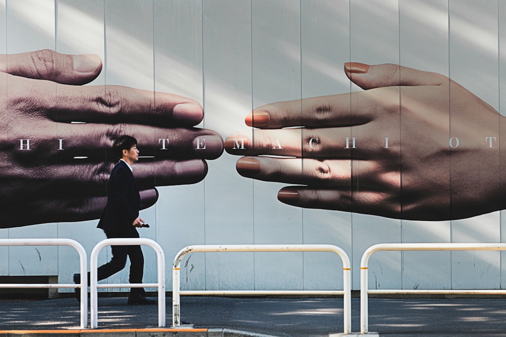 A man in a suit walking past a fence with a large advertisement