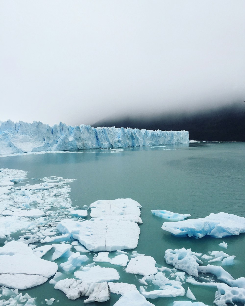 Iceberg sur plan d’eau sous ciel nuageux