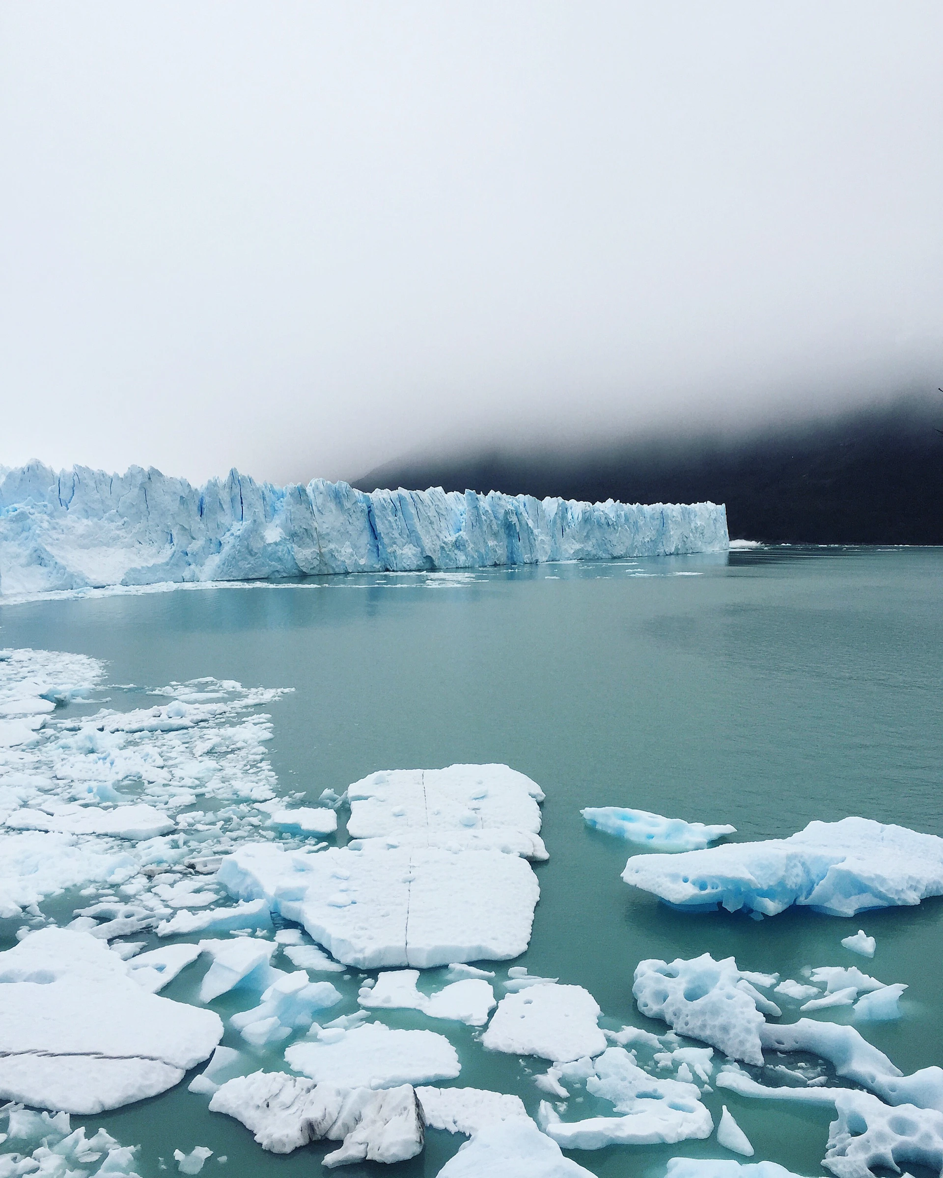 iceberg on body of water under cloudy sky