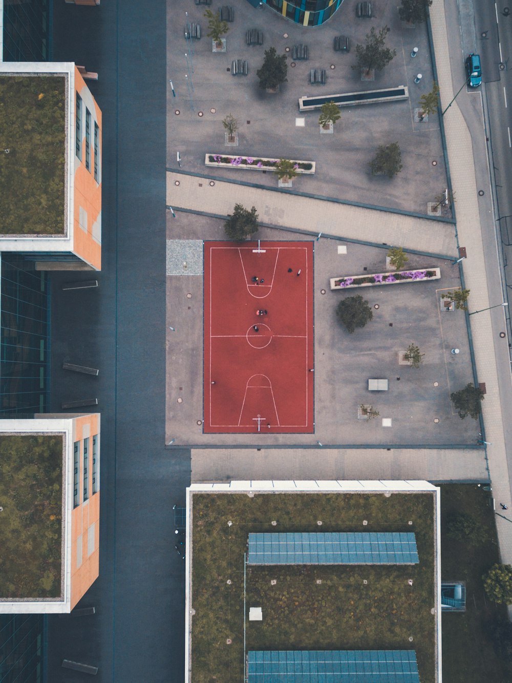 terrain de basket-ball rouge près des bâtiments en photographie aérienne