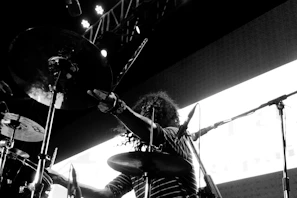 Drummer mid-beat, sticks flying as sweat glistens on their forehead