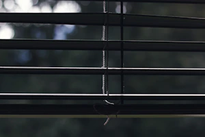 Hands holding a roller blind mechanism part against a window background