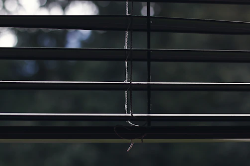 Hands holding a roller blind mechanism part against a window background