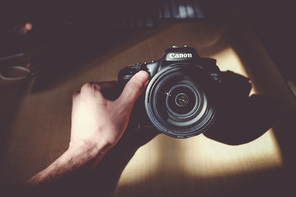 person holding Canon DSLR camera