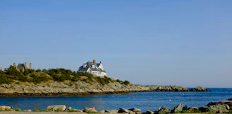 Wide-angle view of a sleek coastal house with glass facades and green living roof overlooking blue sea.