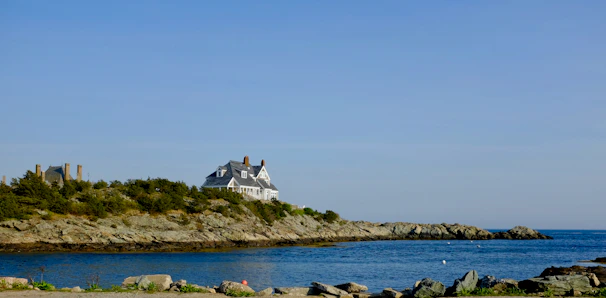 Wide-angle view of a sleek coastal house with glass facades and green living roof overlooking blue sea.