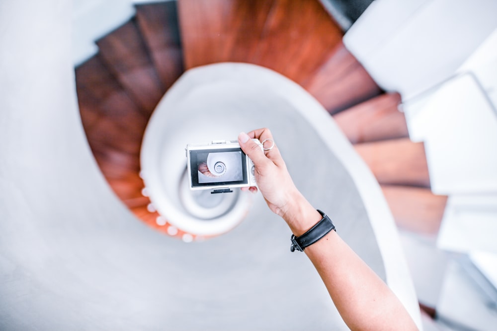 personne prenant une photo de l’escalier en colimaçon blanc