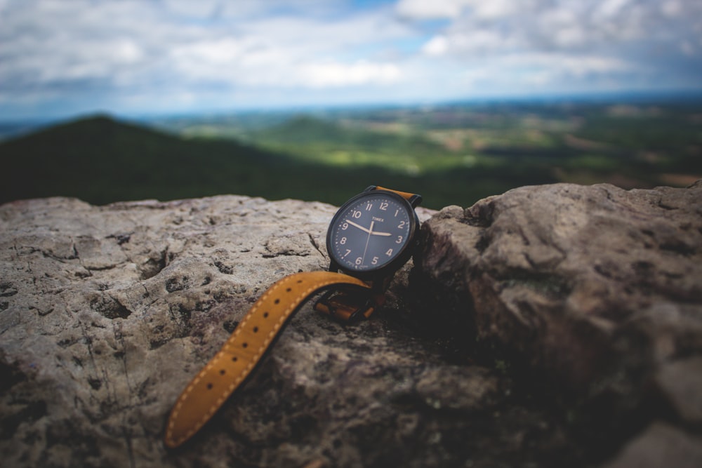 round black analog watch on stone