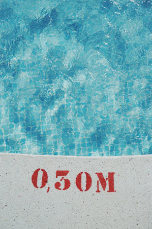 Technician carefully inspecting an in-ground pool liner with measuring tools on a sunny day.