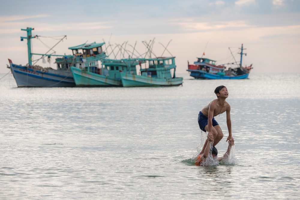 person swimming on sea near ships during daytime