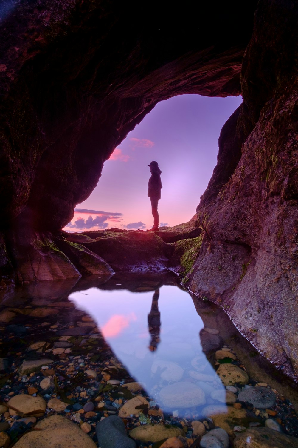 uomo in piedi davanti alla grotta