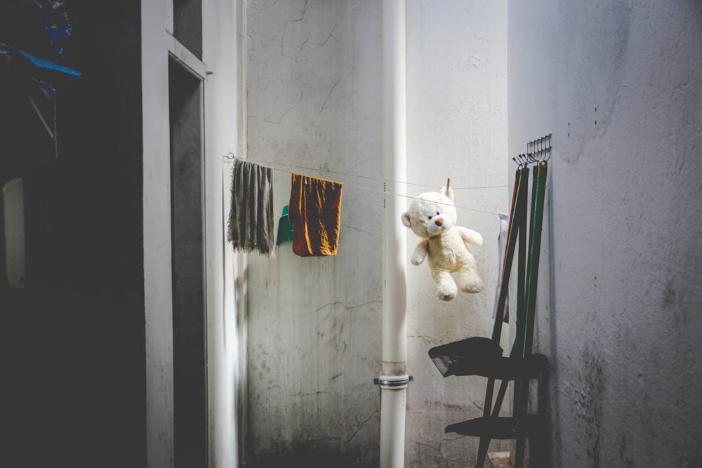brinquedo de pelúcia do urso branco pendurado perto da parede branca
