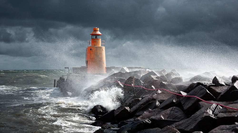 Orangefarbener Leuchtturm auf Felsen