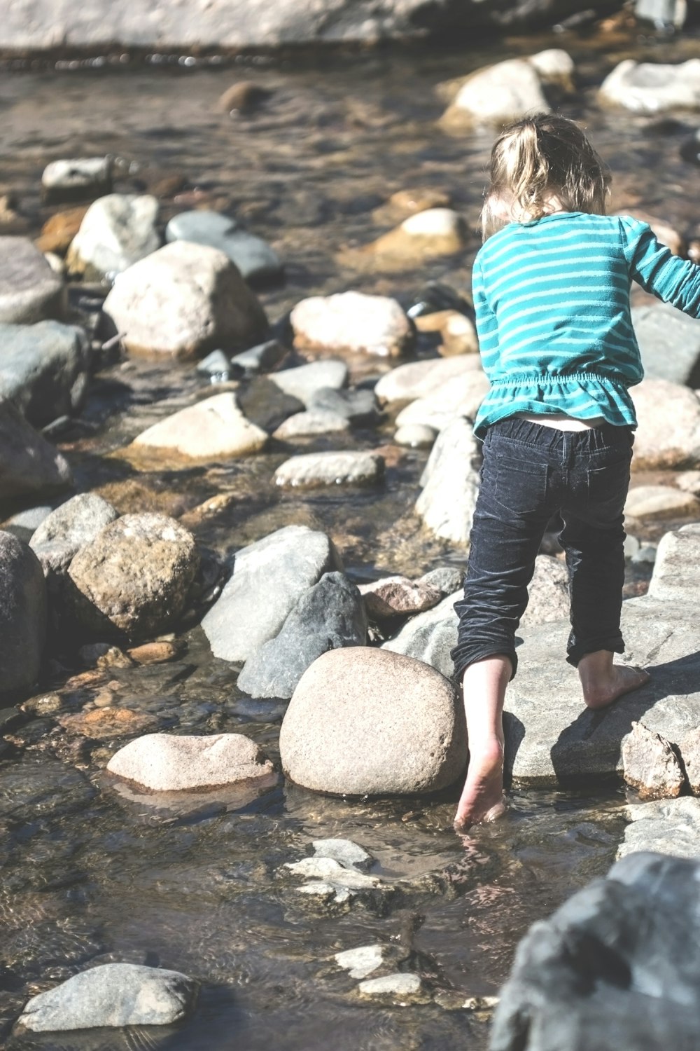 a little girl standing on a rock in a river