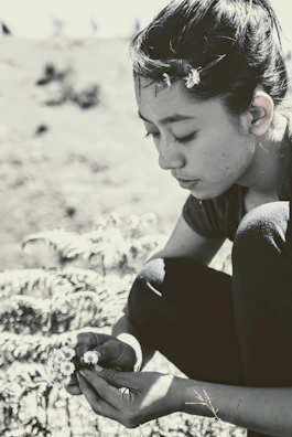 A little girl examining a flower closely during a nature walk.