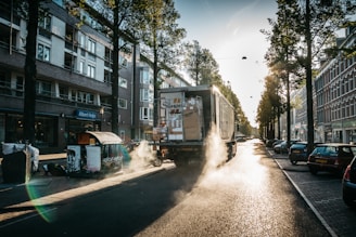 truck moving on gray concrete road between trees