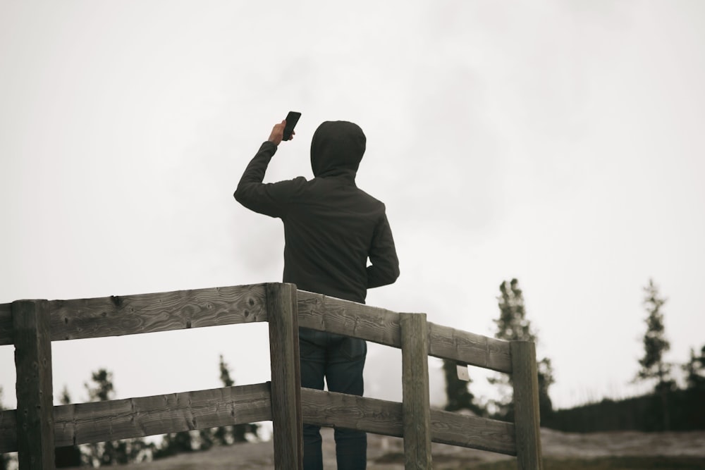 person wearing hoodie holding smartphone