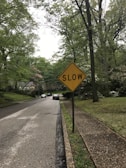 A quiet neighborhood street in Hawaiʻi with clear signage reminding drivers to slow down and drive responsibly.