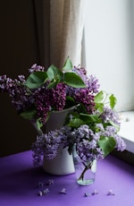 purple flower with green leafed on table